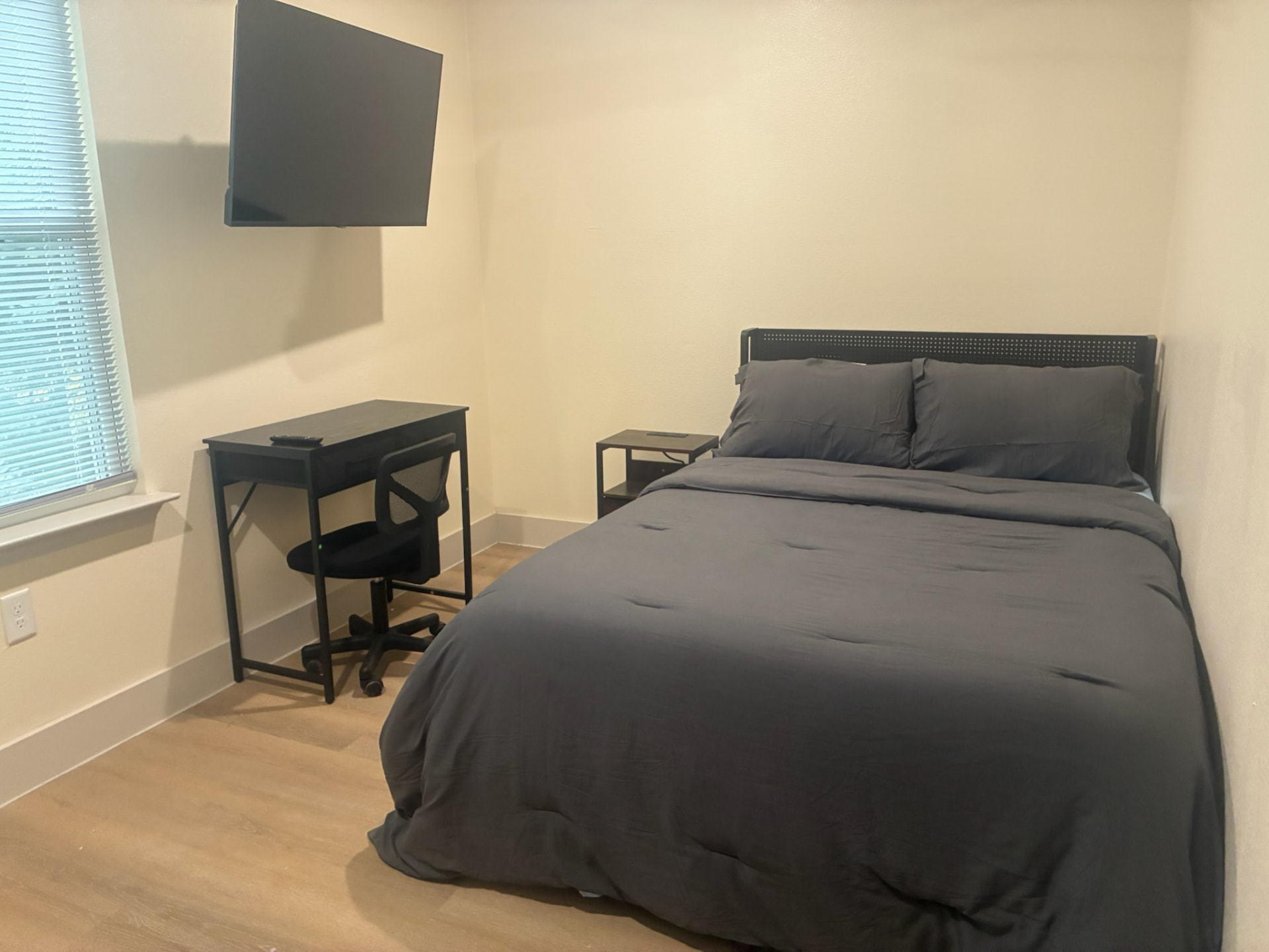 Private bedroom with mounted smart TV, desk and office chair