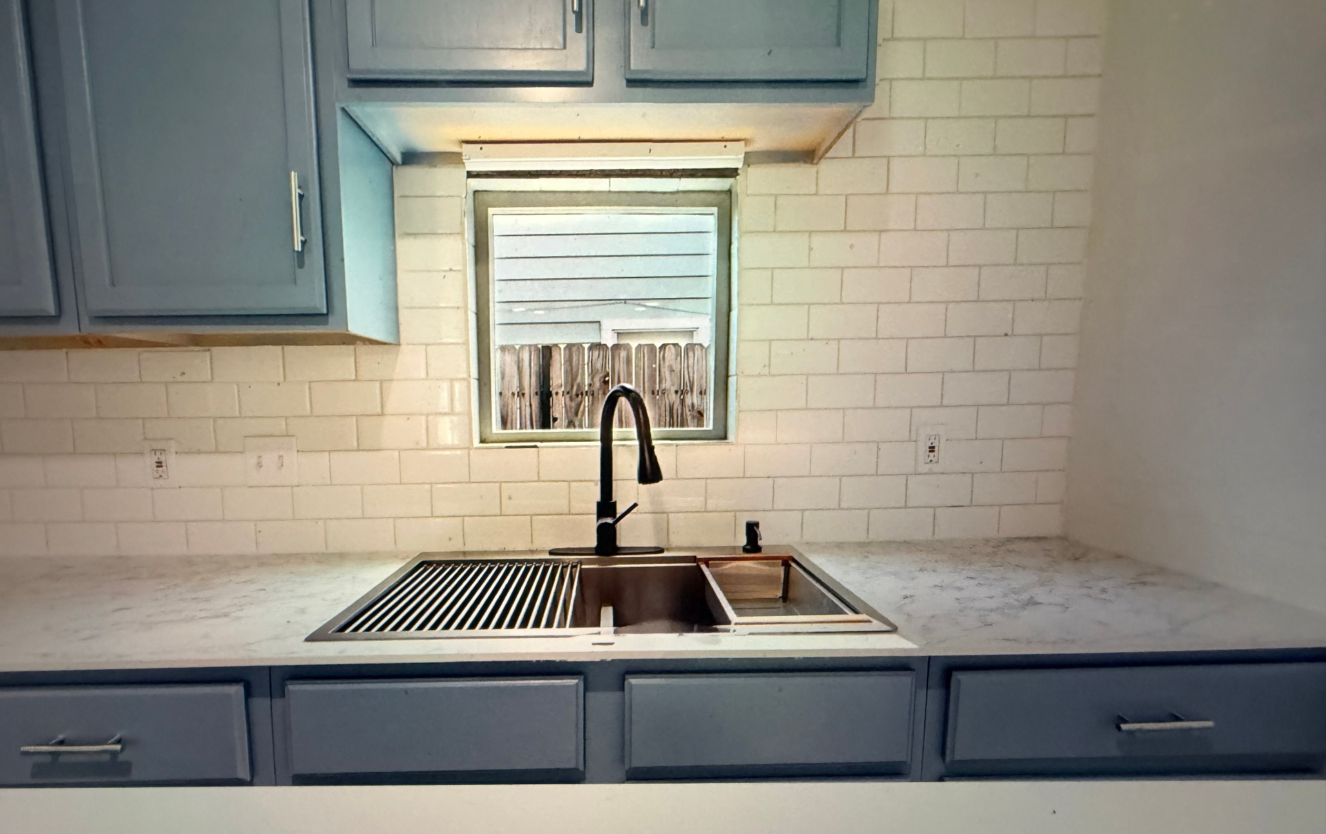 Cosby House — kitchen sink with black faucet, marble counters and window view