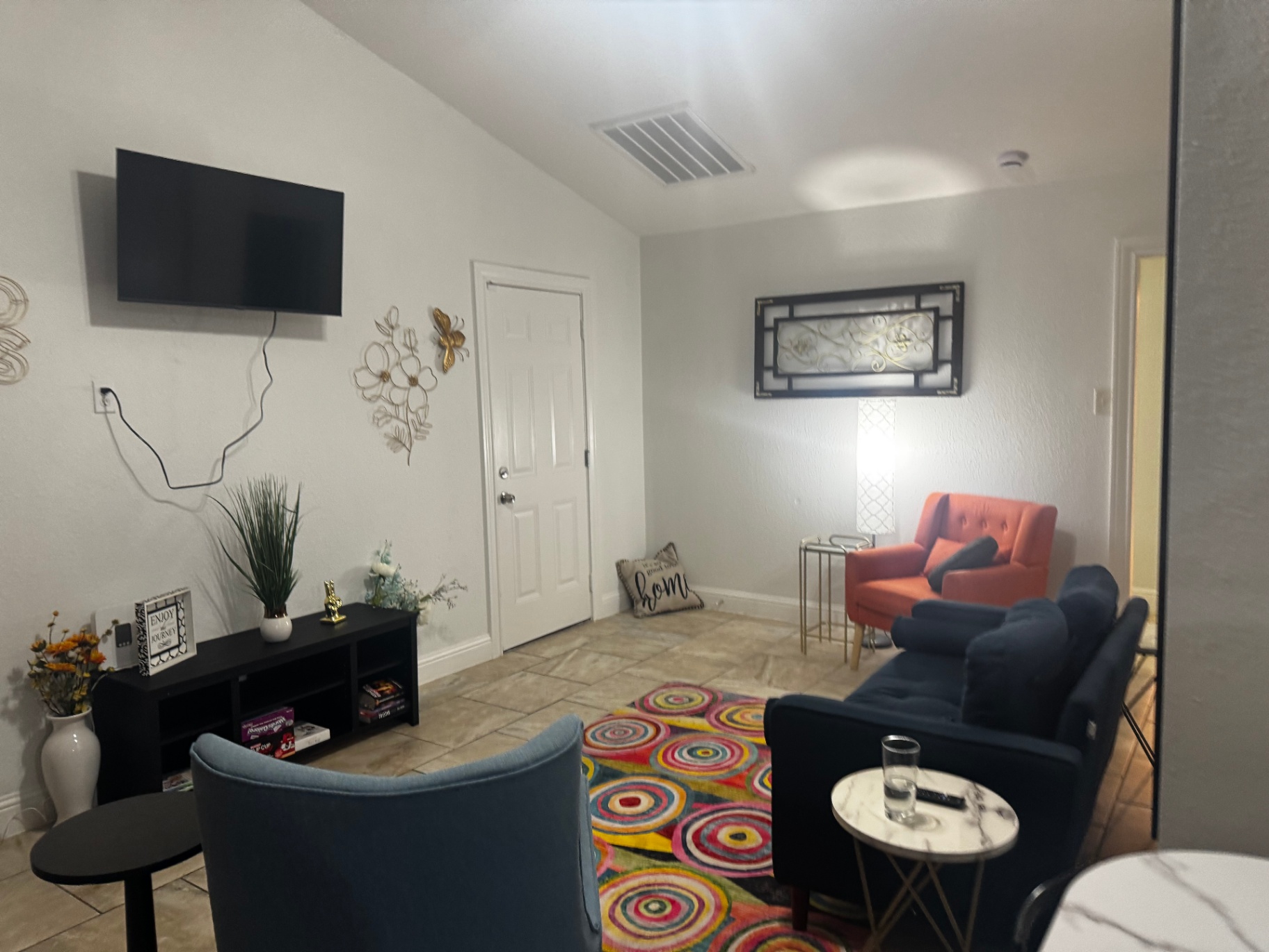 Rinn House — shared lounge with mounted TV, coral chair and games