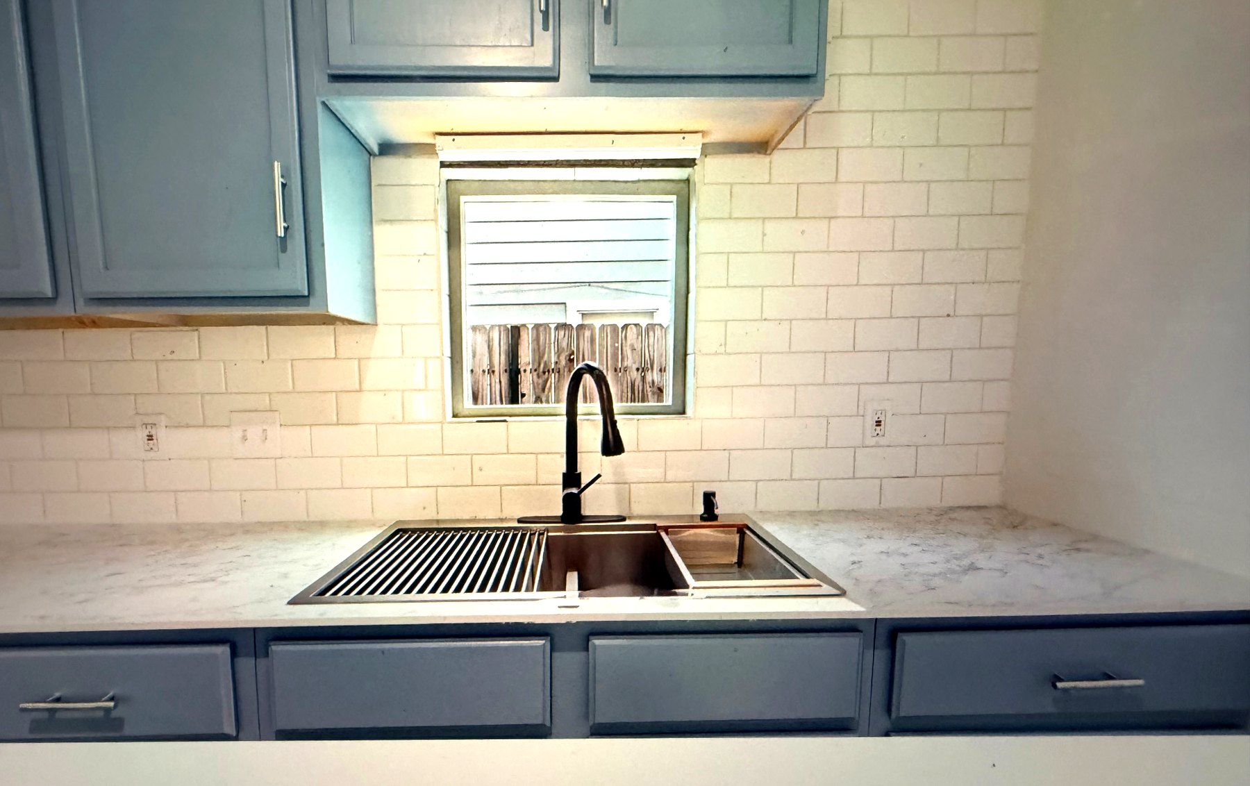 Cosby House — kitchen sink with black faucet, marble counters and window view