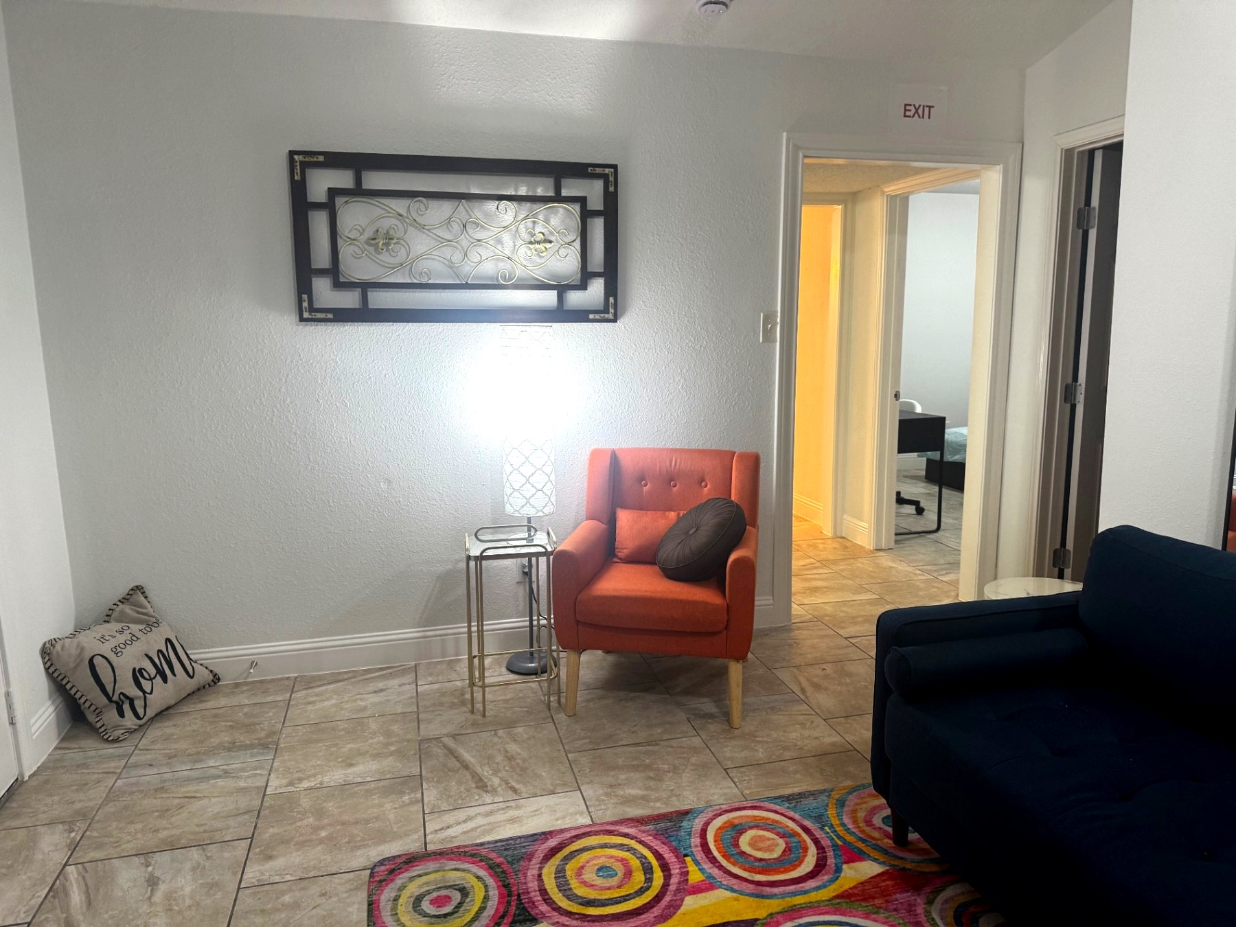 Rinn House — sitting area with orange accent chair and lamp