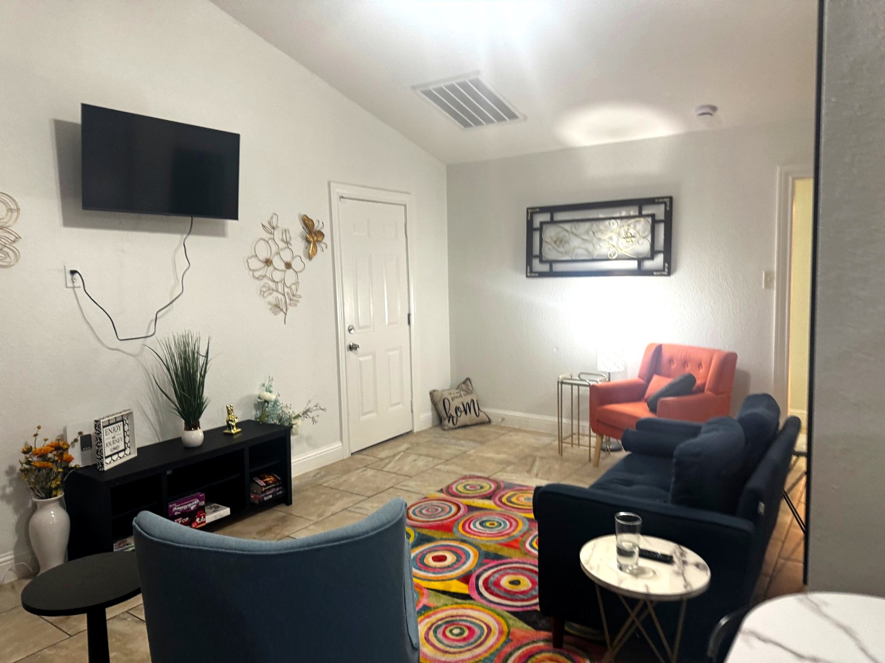 Rinn House — shared lounge with mounted TV, coral chair and games