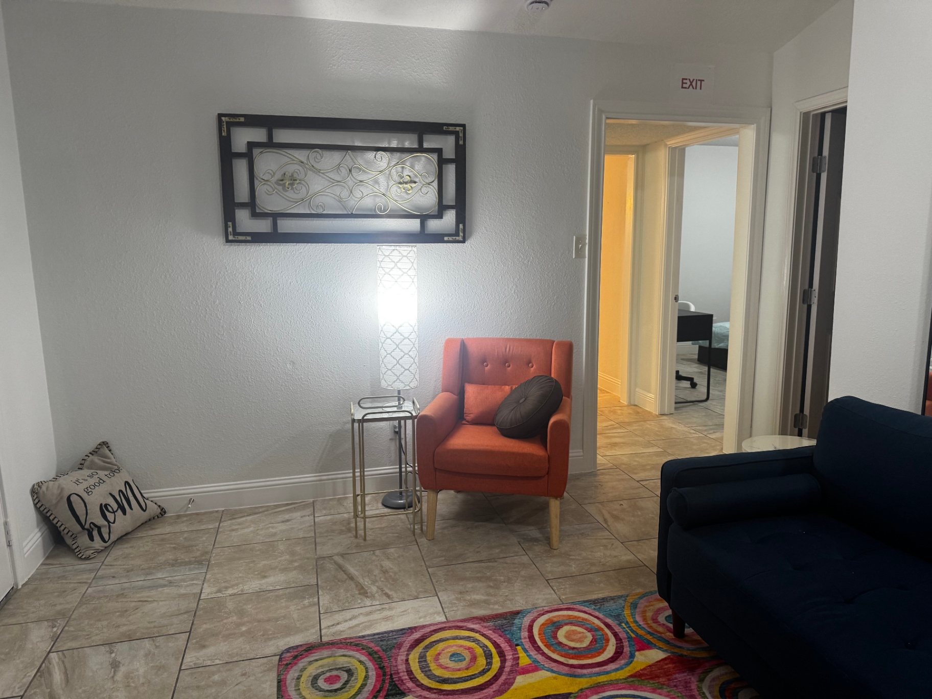 Rinn House — sitting area with orange accent chair and lamp