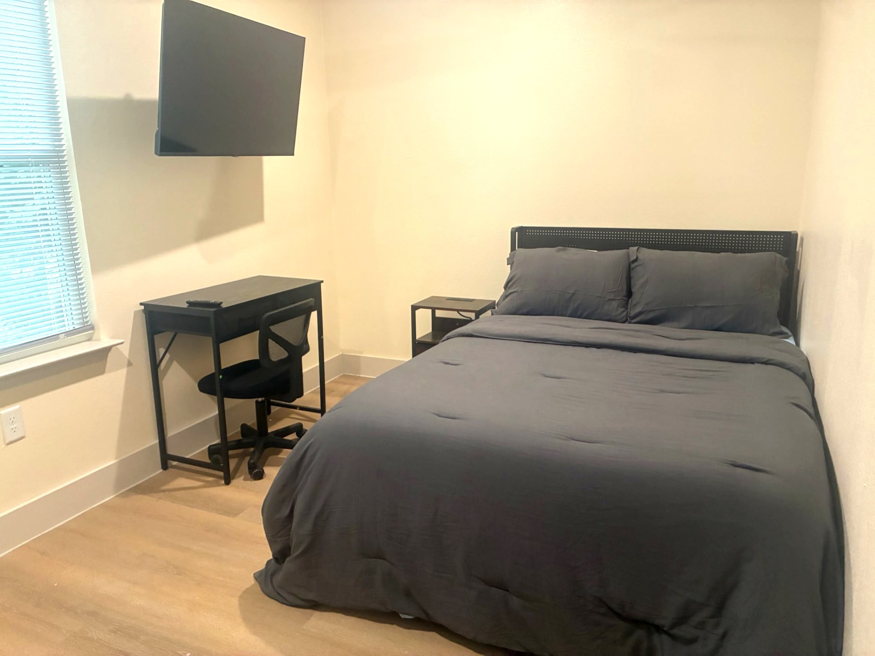 Private bedroom with mounted smart TV, desk and office chair