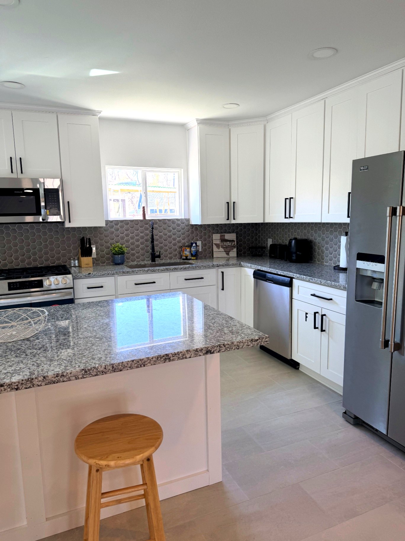 Bright shared kitchen with white cabinets and granite island